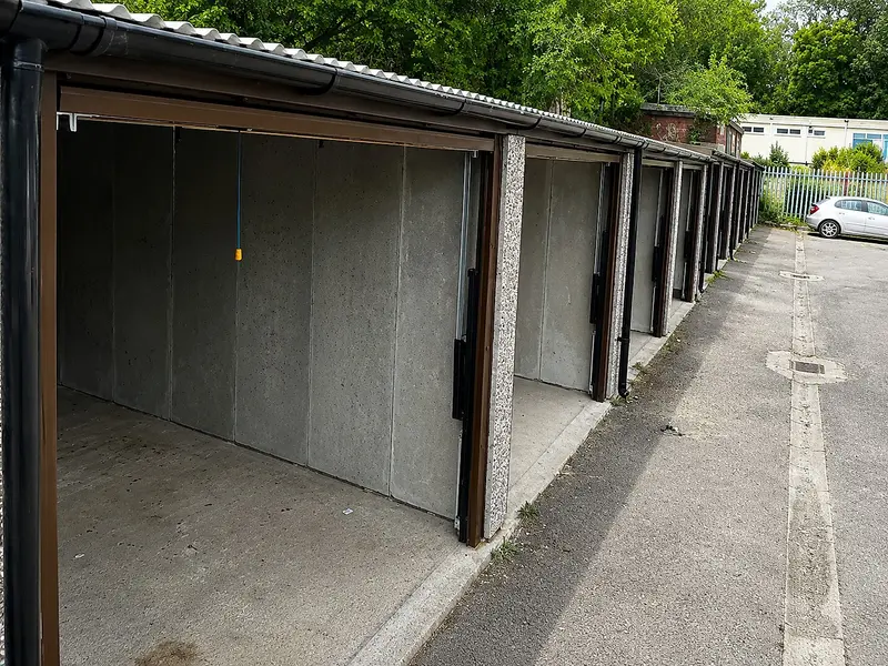 Row of open battery garages showing the bare steel-reinforced concrete panel interiors