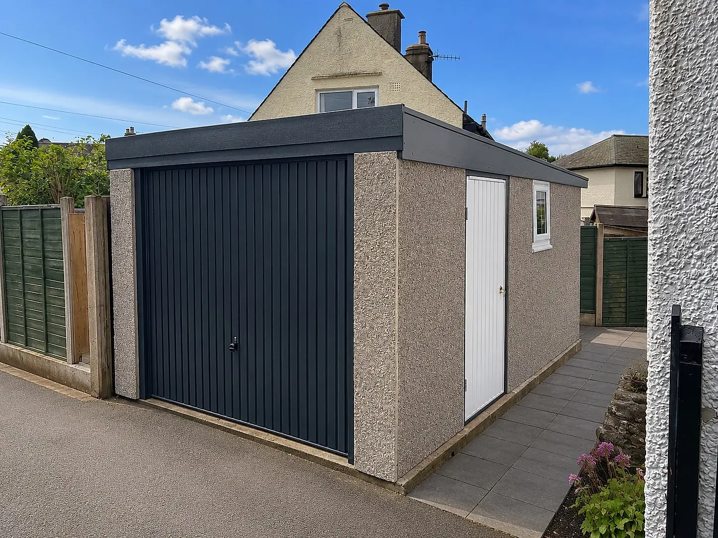 Extra-height pent roof concrete garage with an anthracite up-and-over door and steel personnel door