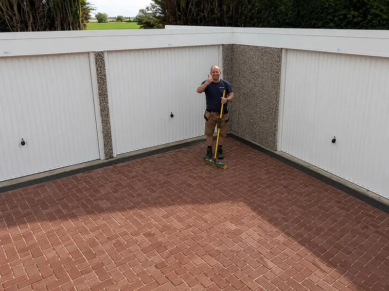 Nucrete fitter in a block-paved courtyard of battery garages arranged around three sides