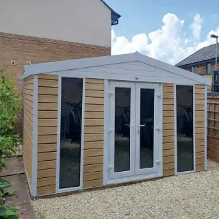 Garden room with light oak composite cladding and a pitched apex roof, viewed from the front