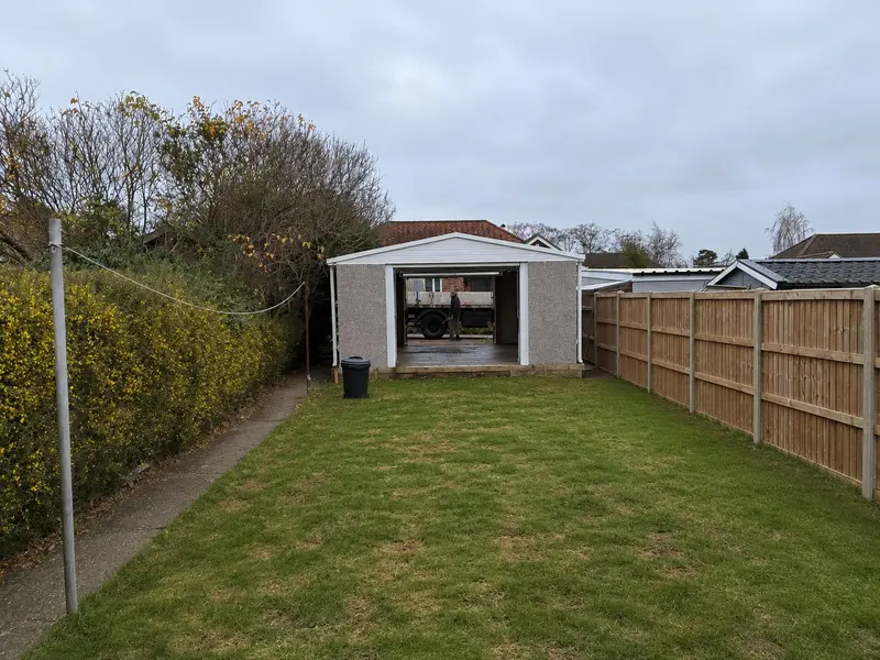 Apex concrete garage with up-and-over doors at both ends on a lawn