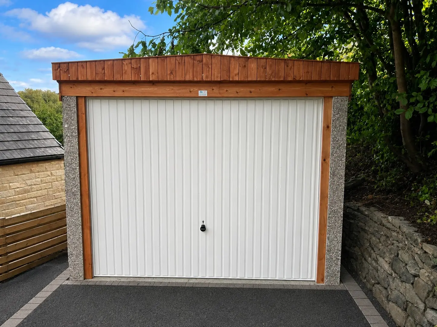 Pent roof concrete garage with a timber fascia on a tarmac driveway