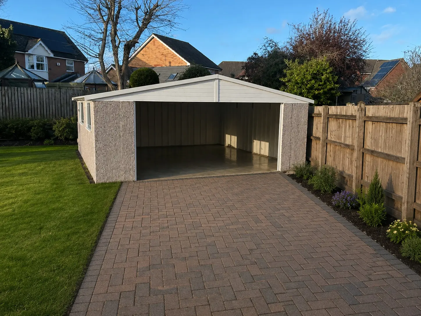 Double Apex concrete garage with the up-and-over doors open on a block-paved driveway