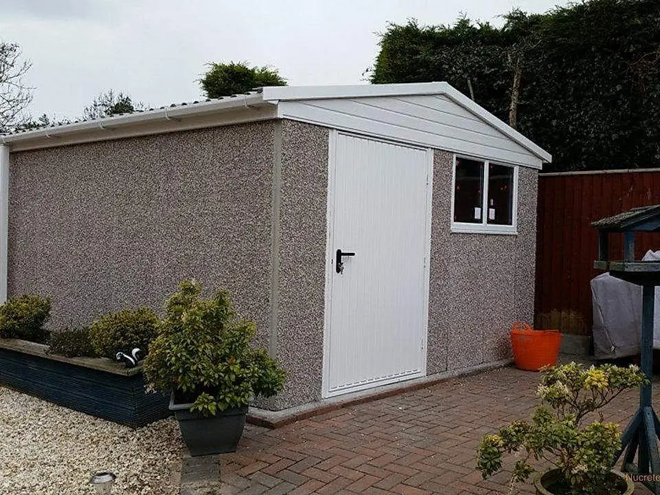 Concrete shed and workshop with pebbledash walls on a block-paved base