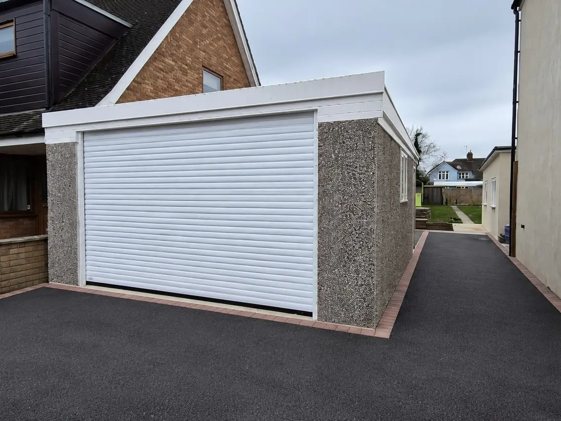 Pent roof concrete garage with a roller door on a tarmac driveway
