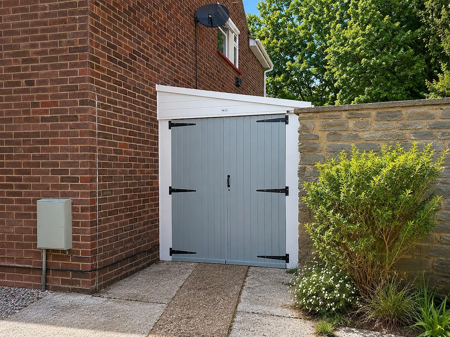 Lean-to concrete garage with grey side-hinged timber doors against a brick house