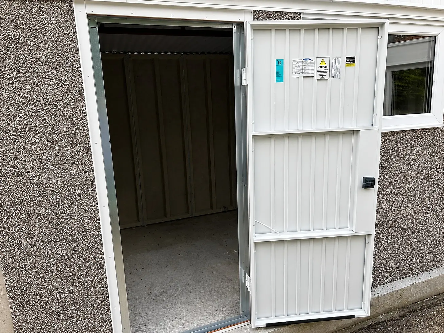 Steel personnel door on an Elite concrete garage, open to show the interior