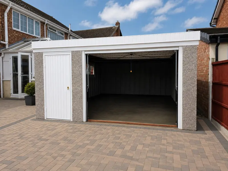 Double pent roof concrete garage with open doors on a block-paved driveway