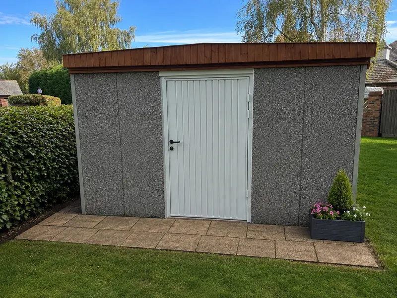 Concrete shed with a pent roof and personnel door on a paved base