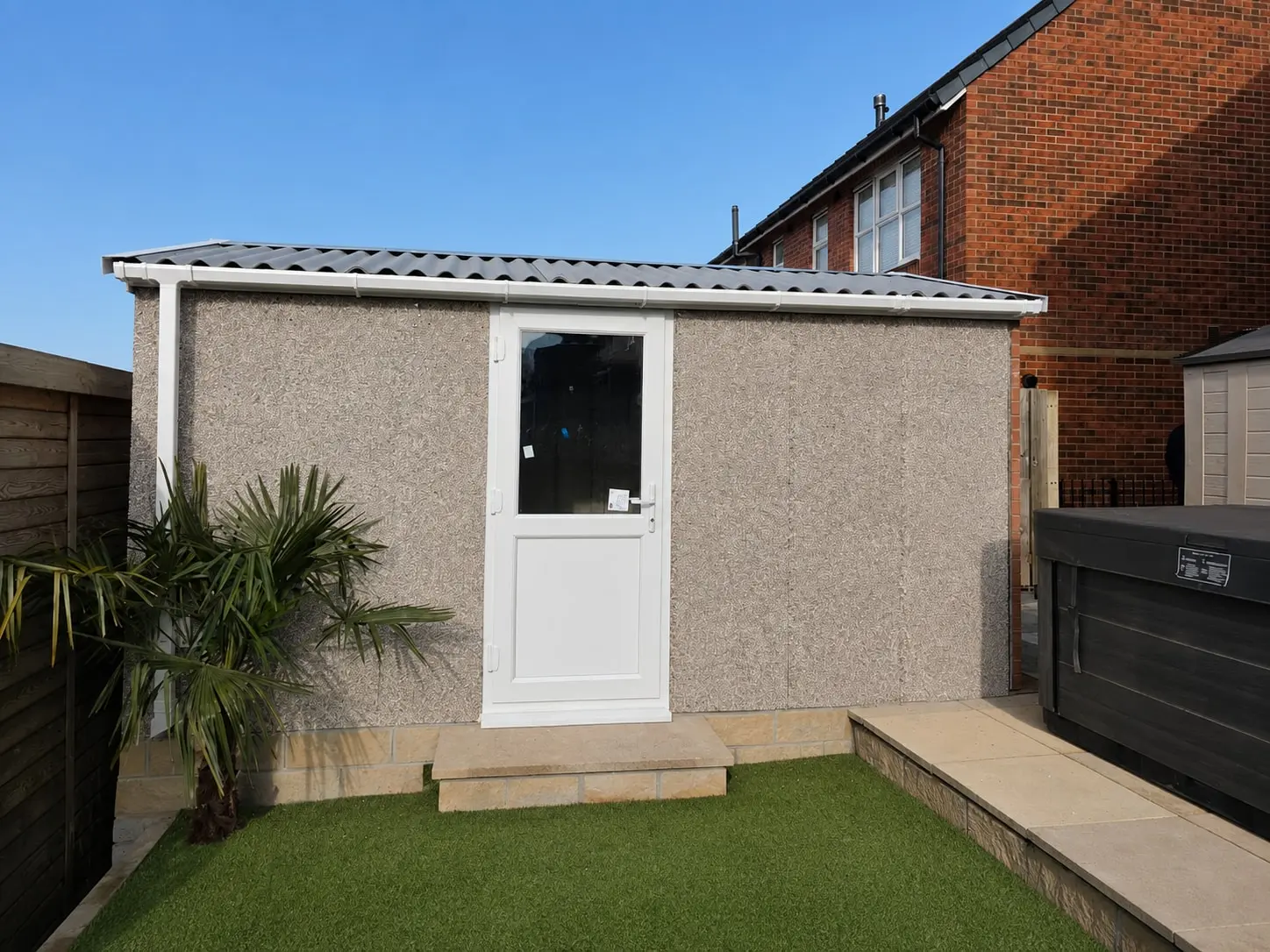 Concrete shed with a uPVC door and window on a landscaped garden