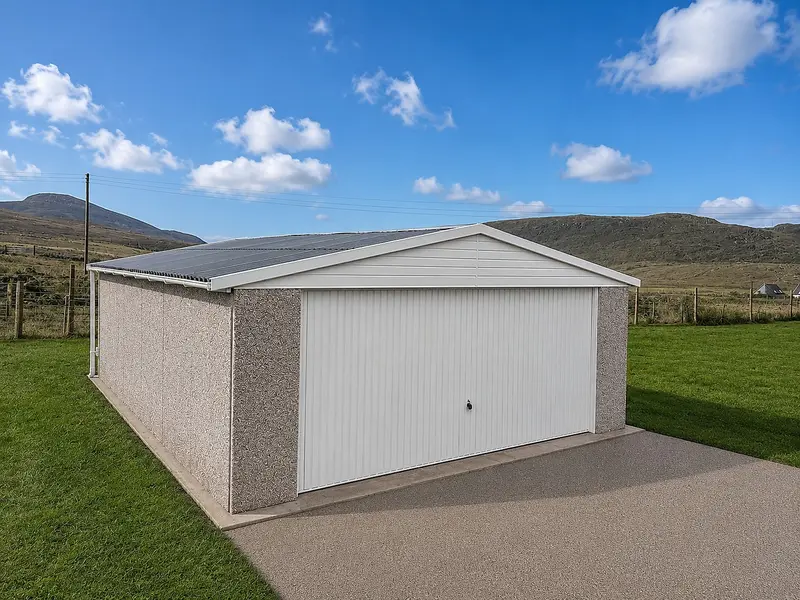 Single apex concrete garage with a white up-and-over door and grey metal roof in a rural setting