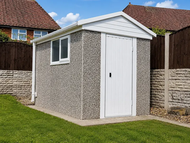 Clean apex-roof concrete shed with a personnel door in a cottage garden