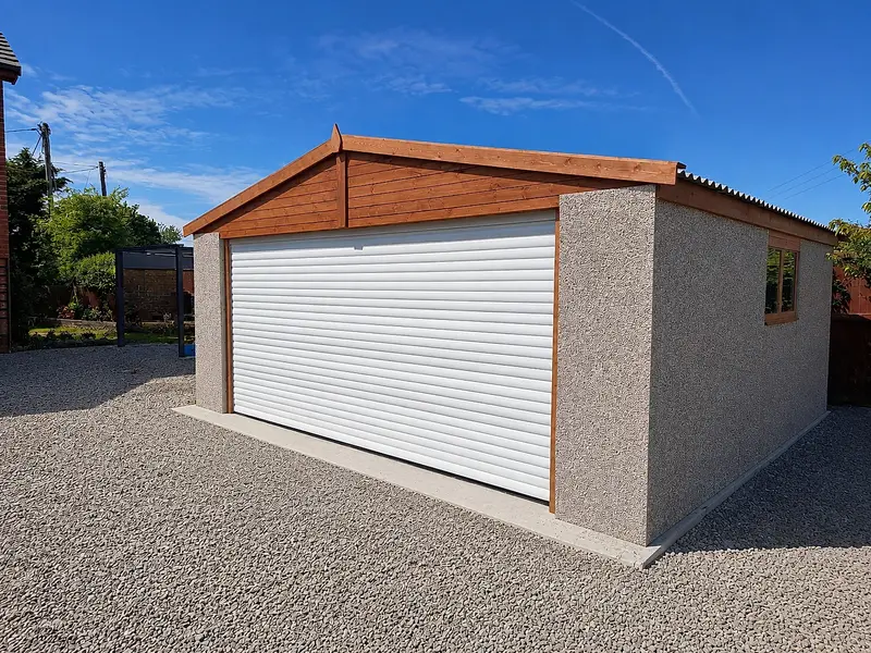 Single apex concrete garage with a white roller door and a cedar-clad gable