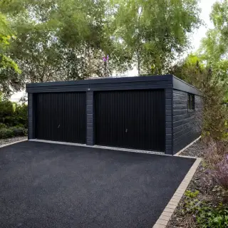 Double garage with anthracite black composite cladding, twin up-and-over doors, and a flat roof set in a landscaped driveway