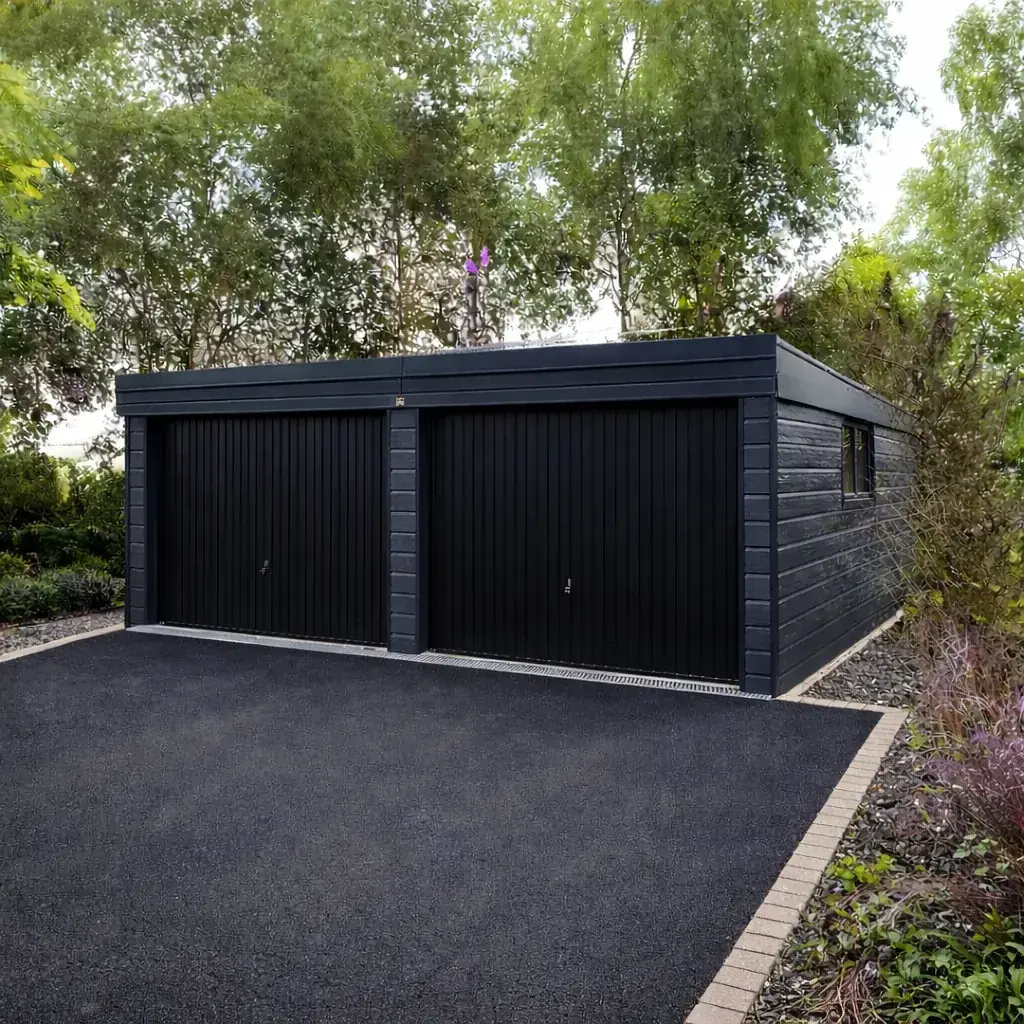 Double garage with anthracite black composite cladding, twin up-and-over doors, and a flat roof set in a landscaped driveway