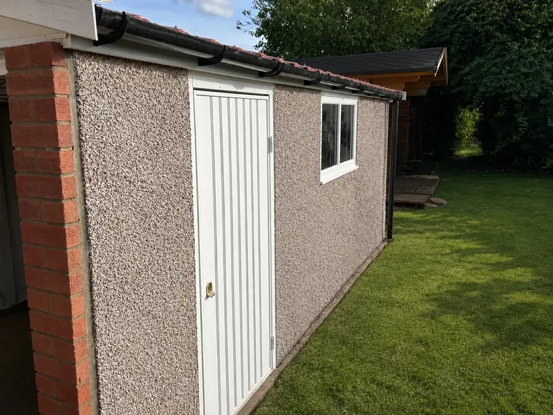 Apex concrete garage with a pebbledash finish and personnel door, side view