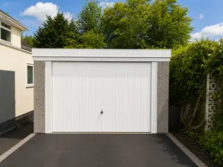 White double pent roof concrete garage on a block-paved driveway